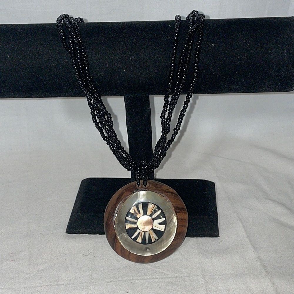 Black beaded necklace with a wooden and shell emblem